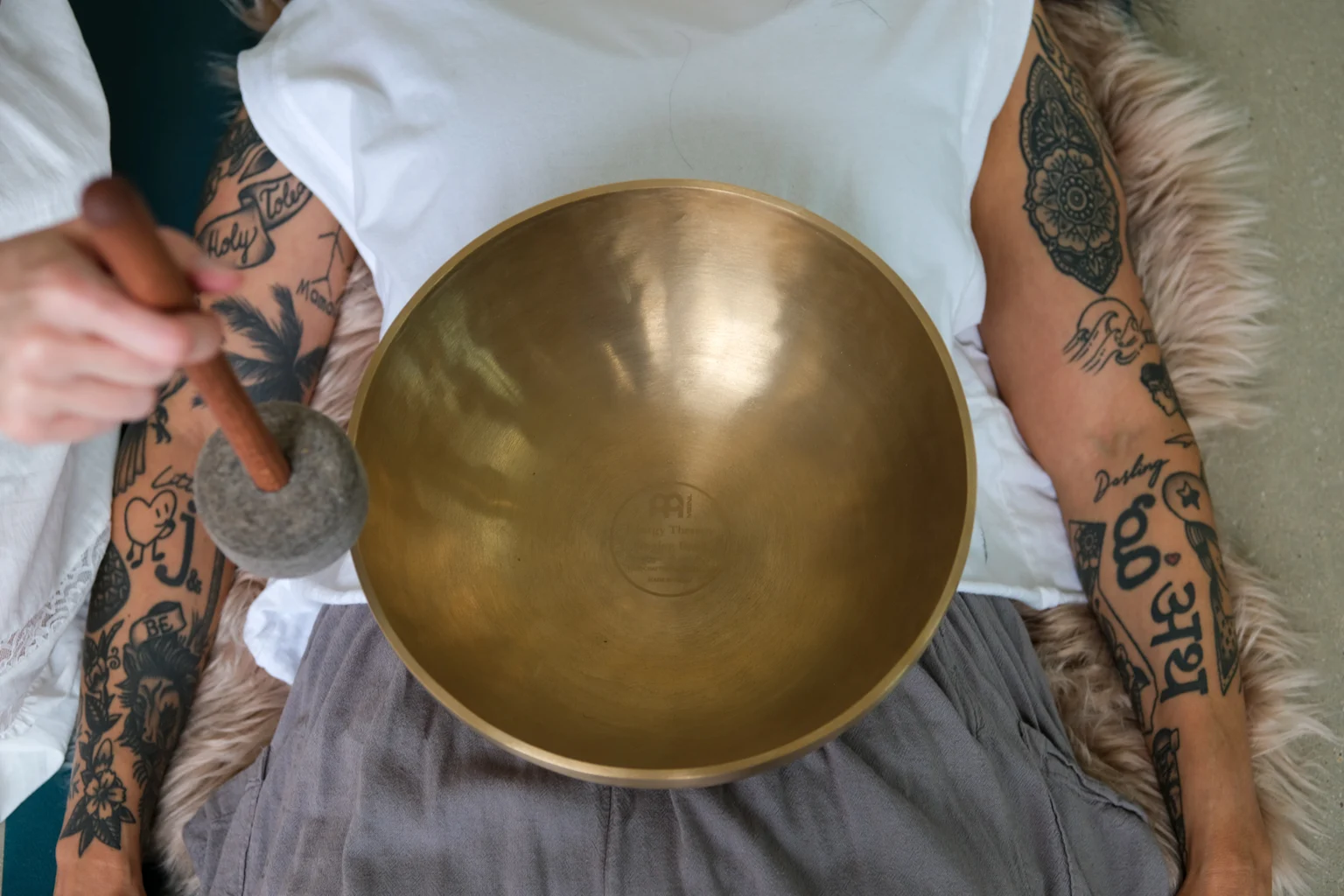 Metal singing bowl resting on the belly during a private sound healing session